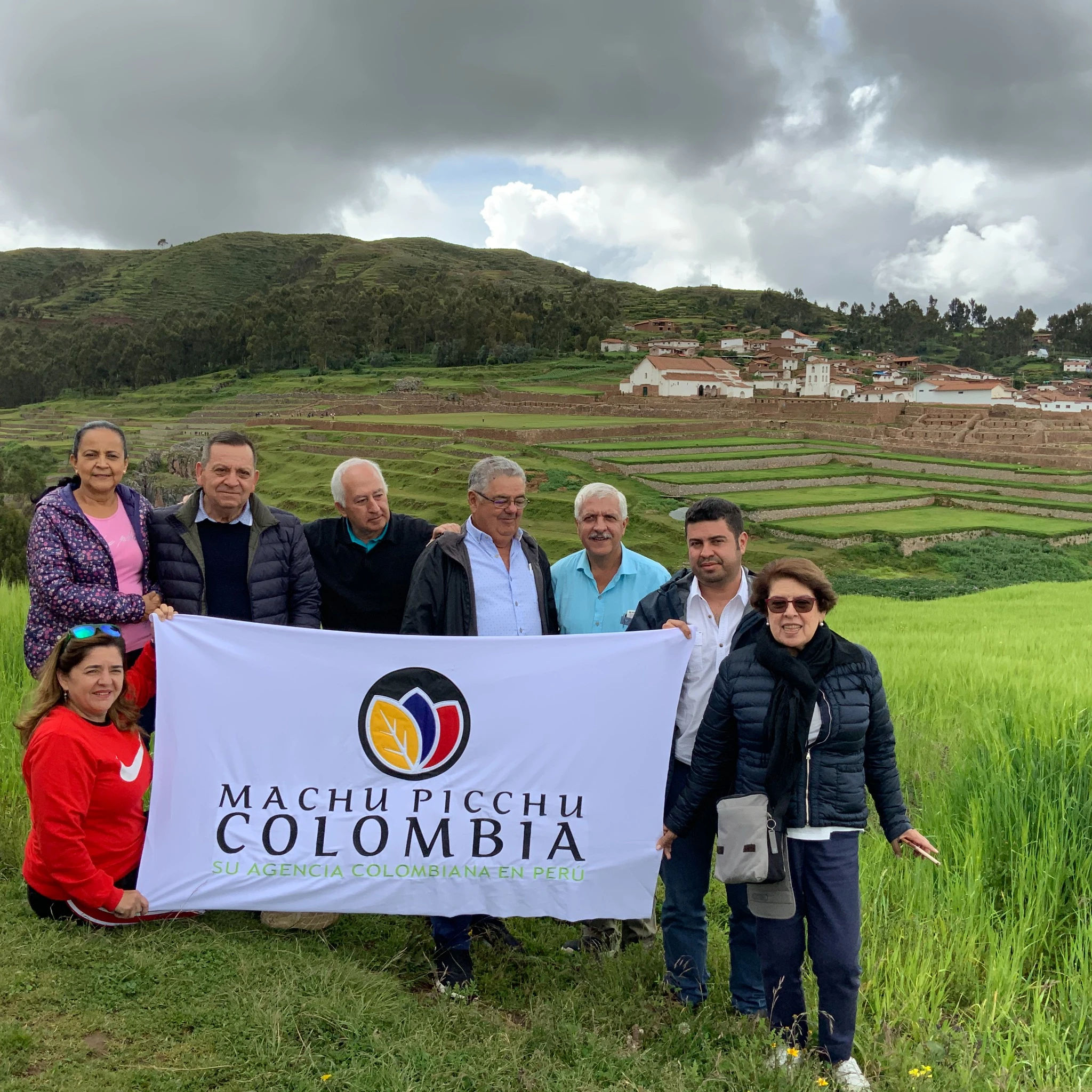 clientes de machu picchu colombia by viajes kintu latinoamerica con la banderola de la empresa en el valle sagrado de cuzco